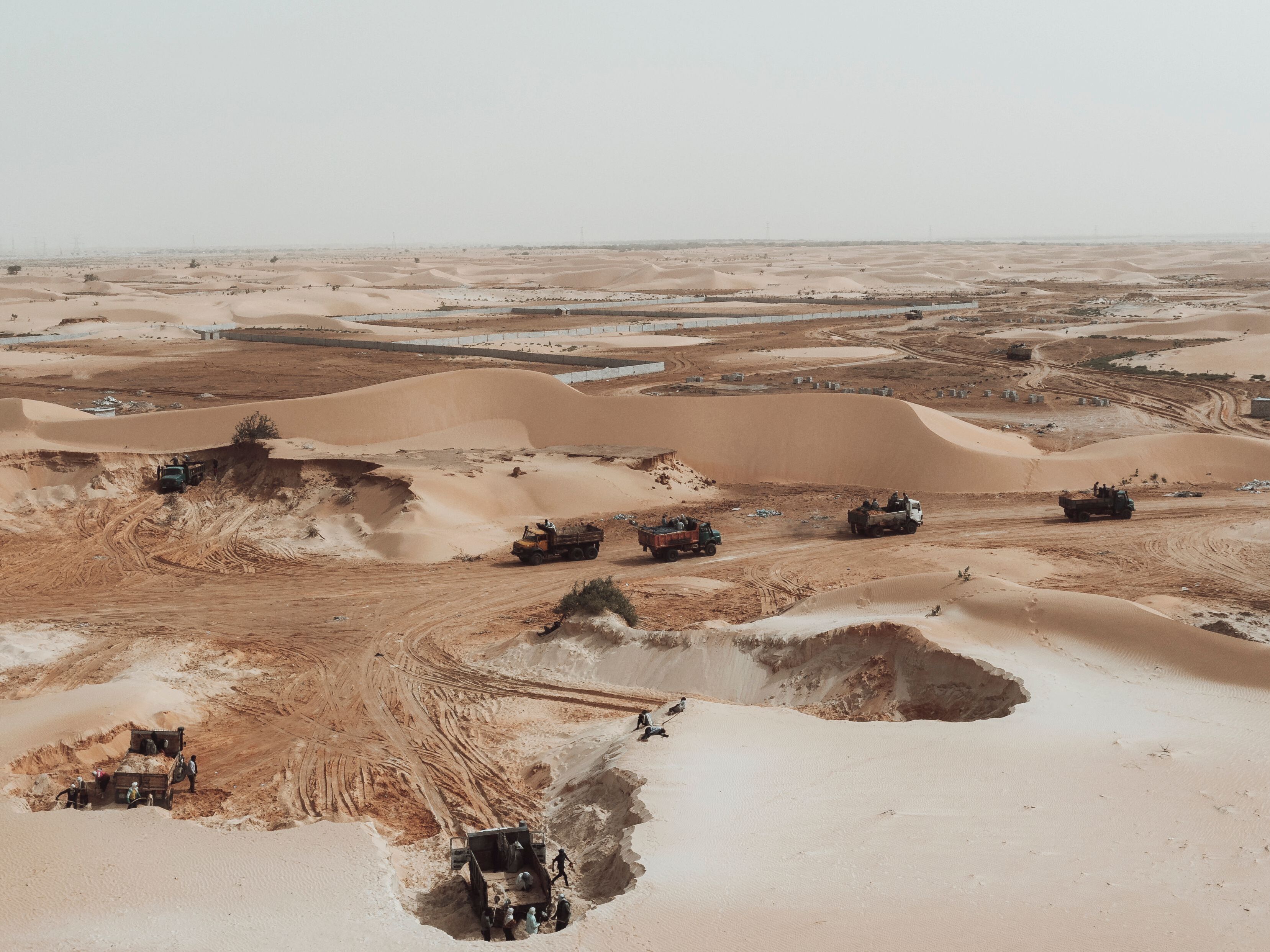 caption: This aerial view show trucks loading sand from a quarry on the outskirts of Nouakchott, Mauritania, on March 14, 2023.
