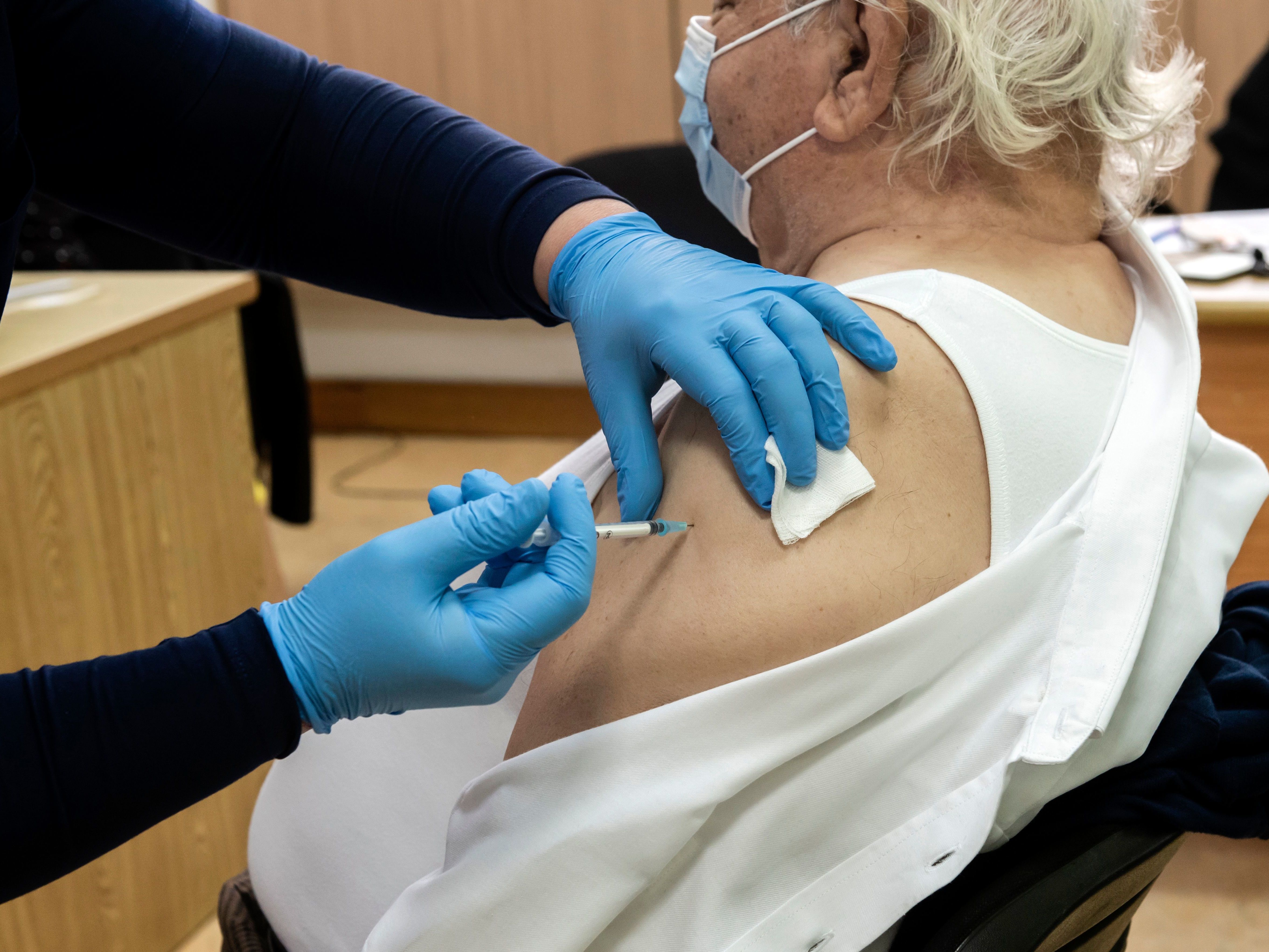 caption: A healthcare worker administers a dose of the coronavirus vaccine to an elderly at a health center in the Cypriot coastal city of Limassol on February 8, 2021.