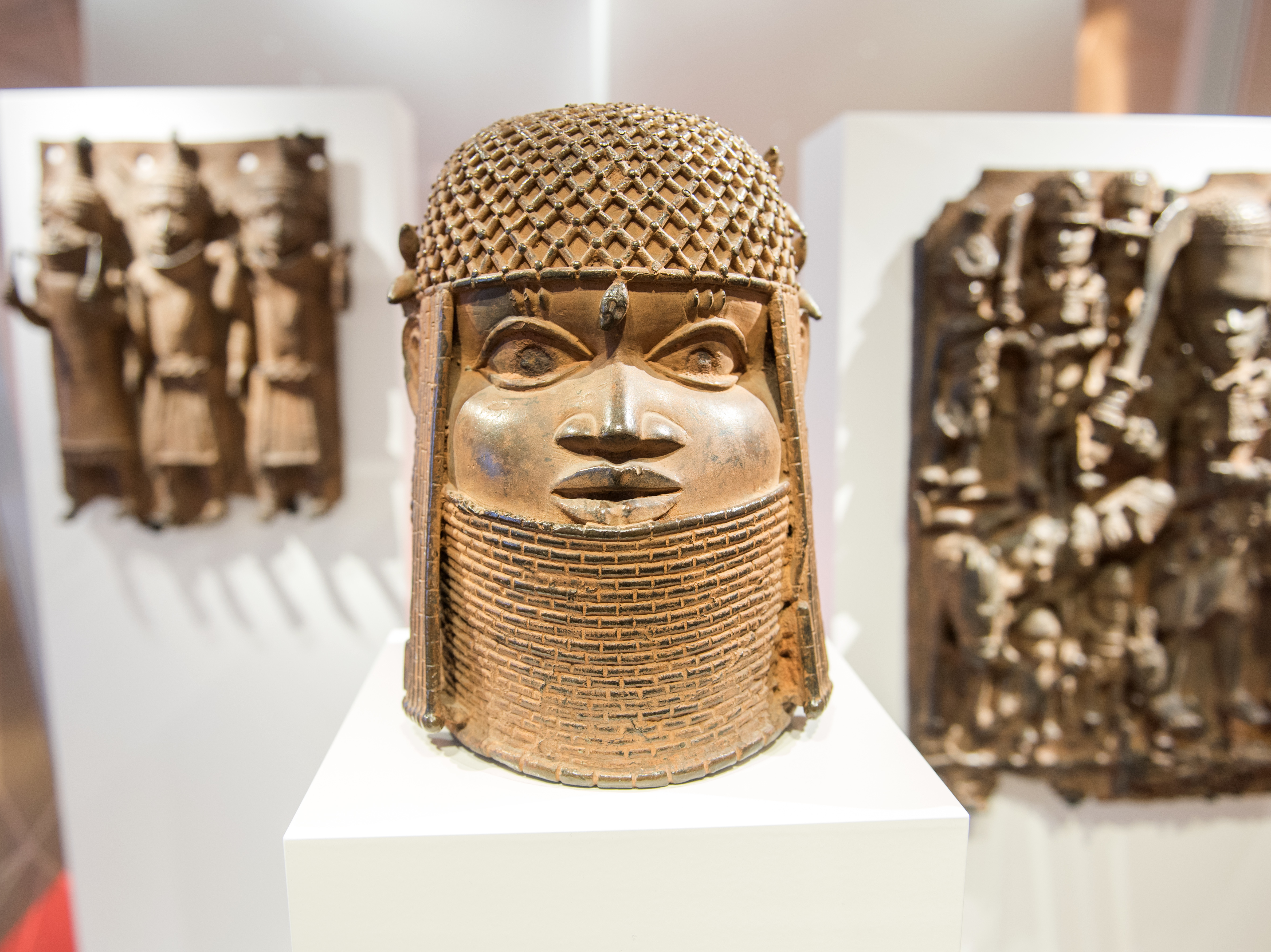 caption: Benin Bronze artifacts on display in the Museum für Kunst und Gewerbe in Hamburg, Germany. An international consortium is working on repatriating artifacts which were looted in the late 19th century.