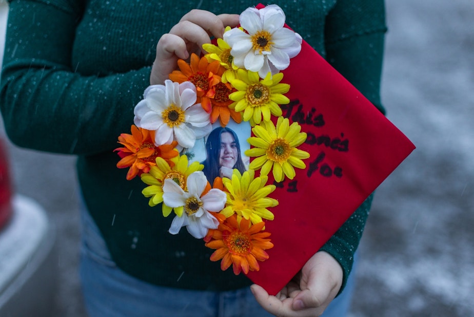 caption: Amythist McCart shows her high school graduation cap adorned with a photo of her friend, missing teenager Kit Nelson-Mora.