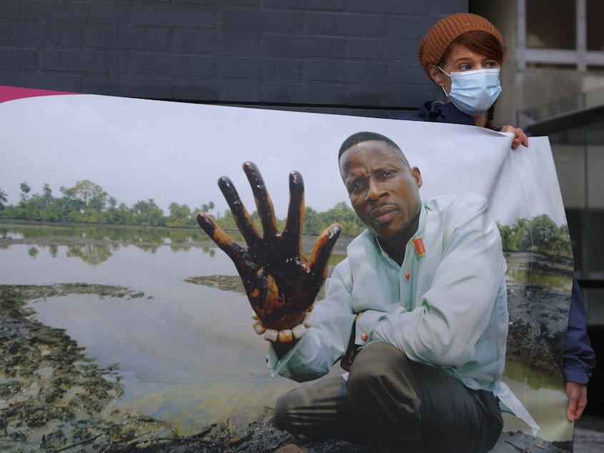 caption: Friends of the Earth supporters unfold a banner on Friday outside the district court in The Hague, Netherlands, where the court delivered its judgment in a long-running case in which four Nigerian farmers are seeking compensation and a cleanup from energy giant Shell for pollution caused by leaking oil pipelines in the Niger Delta.