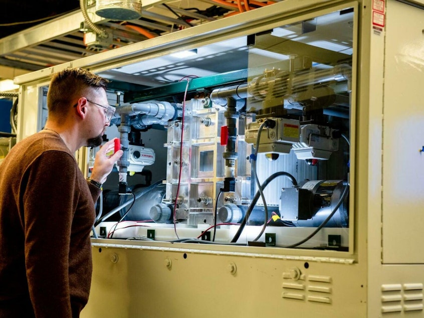 caption: An employee examines a vanadium flow battery stack in the Battery Reliability Test Laboratory at PNNL.