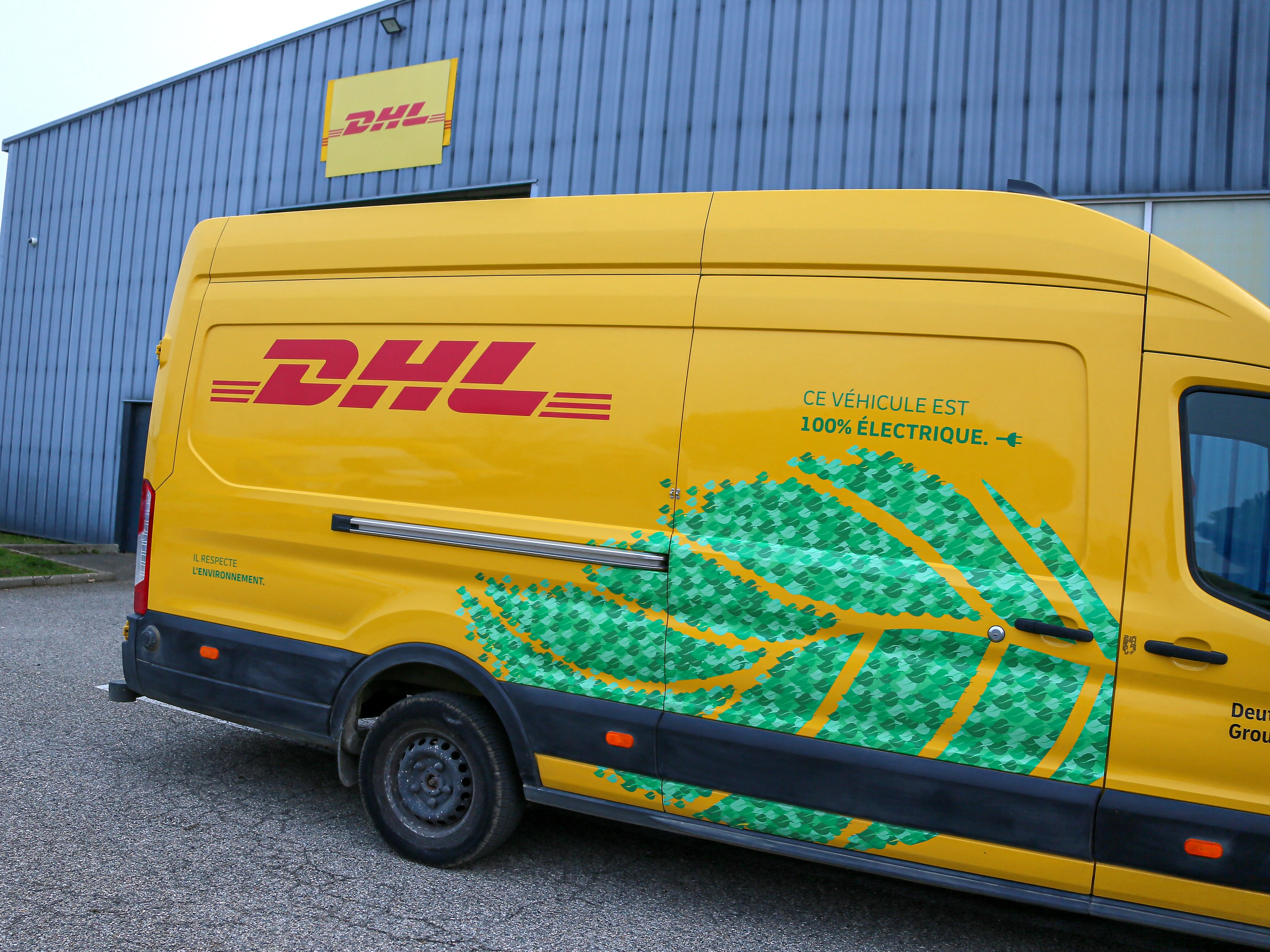 caption: A DHL delivery vehicle is seen in front of a warehouse in Valence, France, in December 2024. The global shipping company announced it would temporarily stop shipping packages valued over $800 to U.S. consumers.