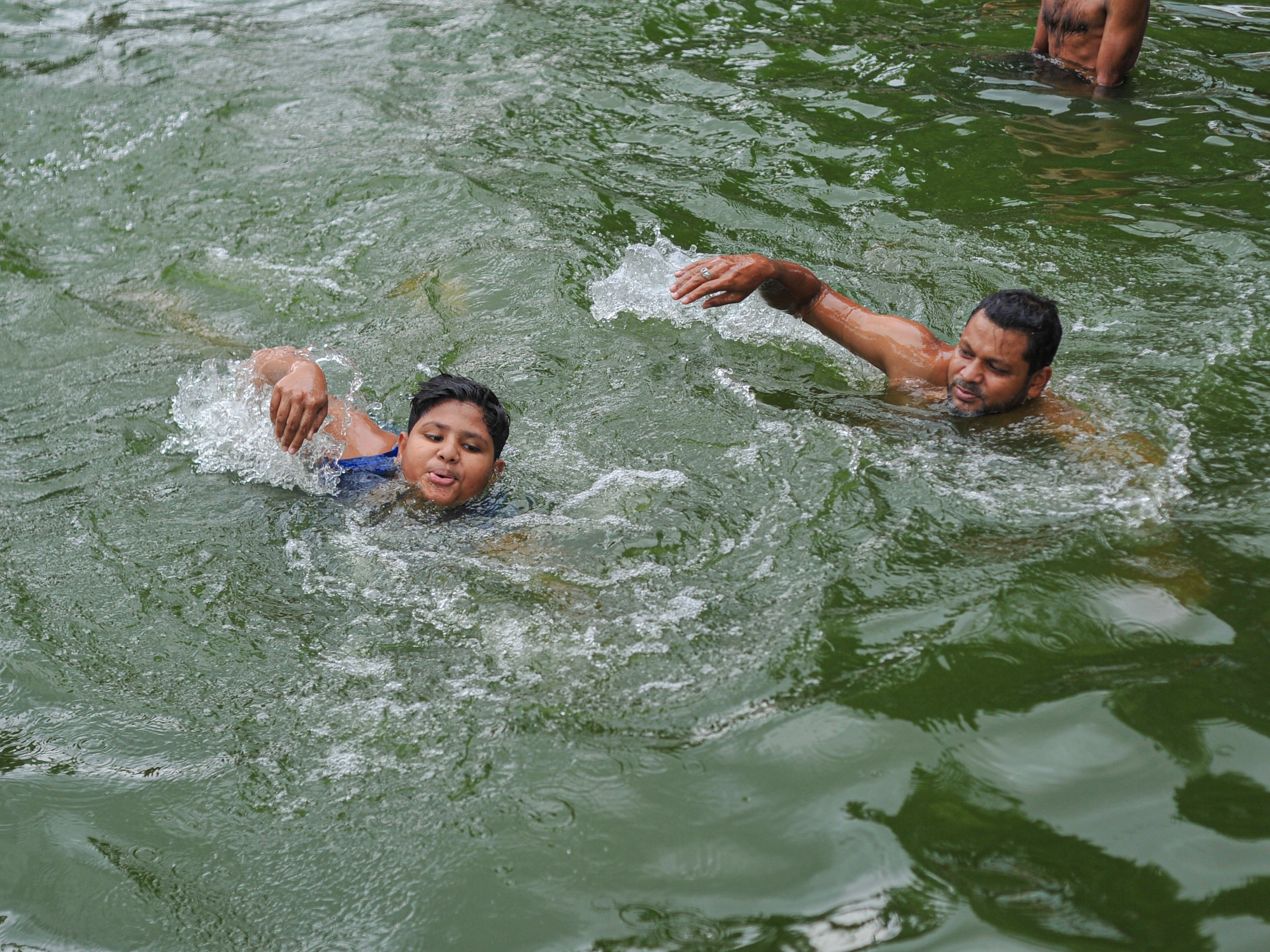 caption: A father teaches his child to swim in a pond in Sylhet, Bangladesh. Drowning is a leading causes of death globally for children, according to the first ever report on drowning as a public health issue issued by the World Health Organization.