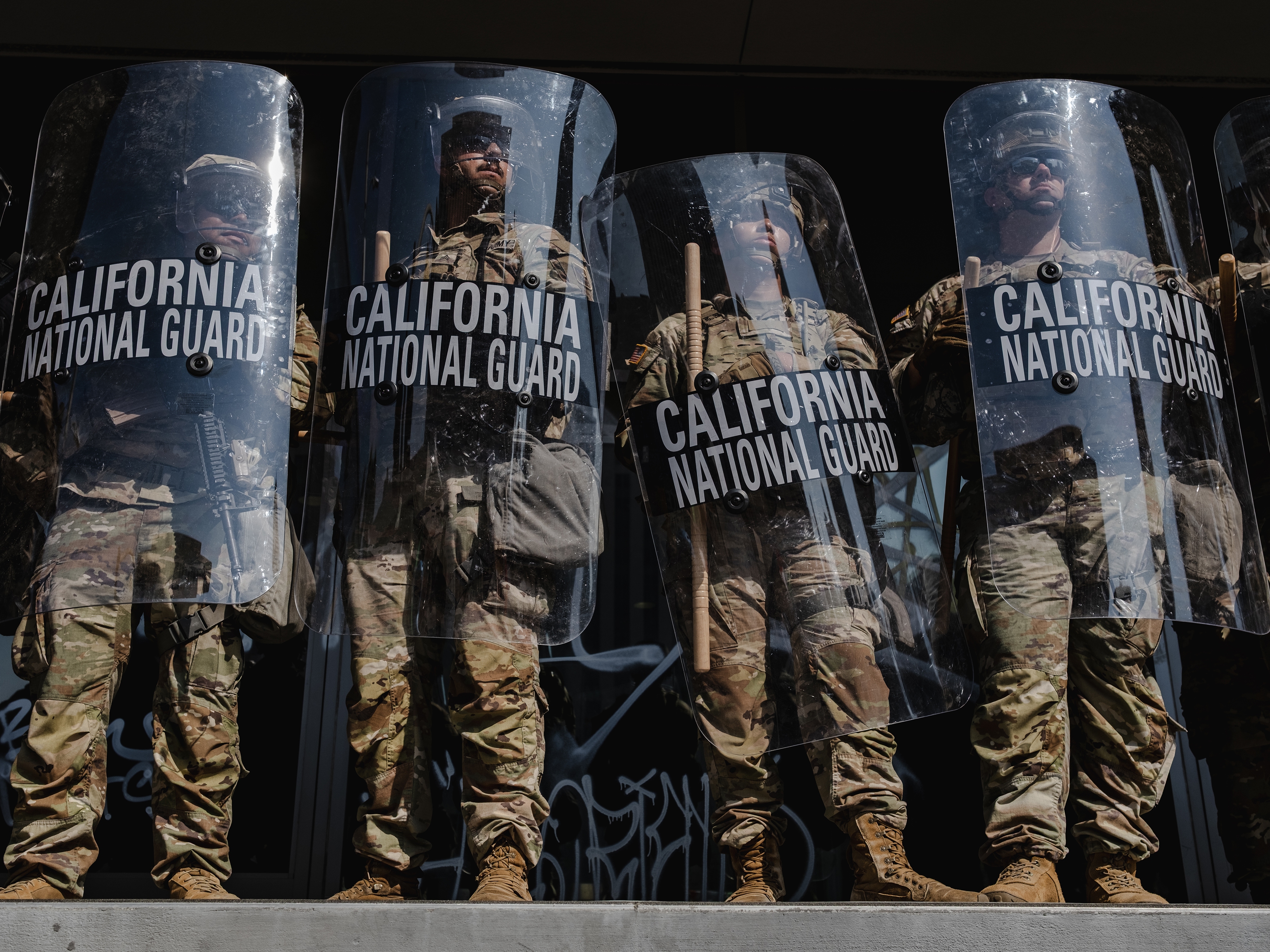caption: National Guardsmen stand outside of the Edward Roybal Federal Building on June 9, 2025 in Downtown Los Angeles, California.