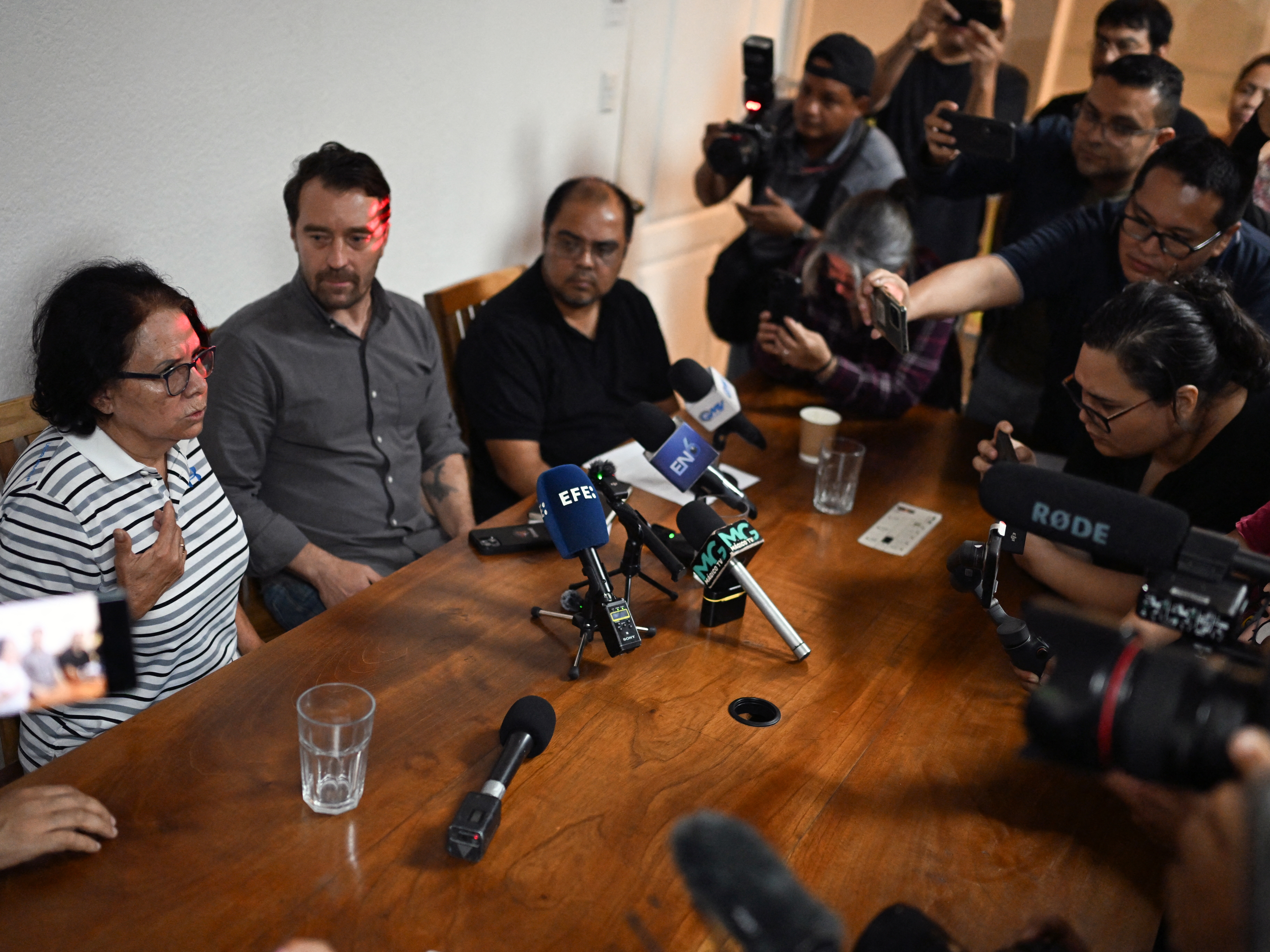 caption: Eleonora Alfaro (L), mother of lawyer Ruth Lopez of the human rights group Cristosal, speaks next to Noah Bullock (C), executive director of Cristosal, and Louis Benavides (R), partner of Lopez, during a press conference in El Salvador.