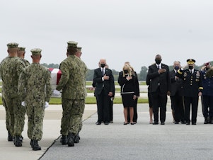 caption: President Joe Biden watches as a Navy carry team moves a transfer case containing the remains of Navy Corpsman Maxton W. Soviak, 22, of Berlin Heights, Ohio, Sunday, Aug. 29, 2021, at Dover Air Force Base, Del.  (AP Photo/Manuel Balce Ceneta)