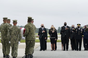 caption: President Joe Biden watches as a Navy carry team moves a transfer case containing the remains of Navy Corpsman Maxton W. Soviak, 22, of Berlin Heights, Ohio, Sunday, Aug. 29, 2021, at Dover Air Force Base, Del.  (AP Photo/Manuel Balce Ceneta)
