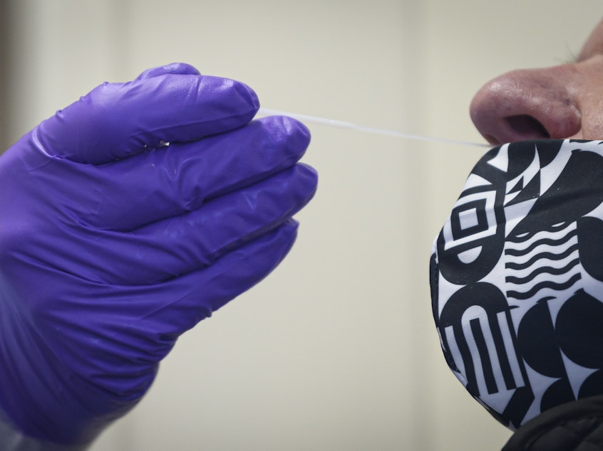 caption: A nurse swabs the nose of a patient as he administers a COVID-19 test. The Food and Drug Administration approved two new rapid, at-home COVID-19 tests for use by Americans Wednesday.