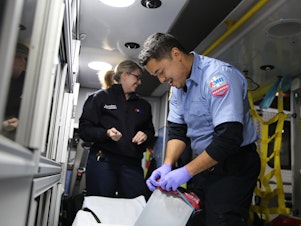 caption: Talitha Saunders and AJ Ikamoto tidy their ambulance at the end of a recent shift. The two work as emergency medical responders in Oregon with American Medical Response in Portland. Leaders there are working to prevent any race-based disparities in treatment.