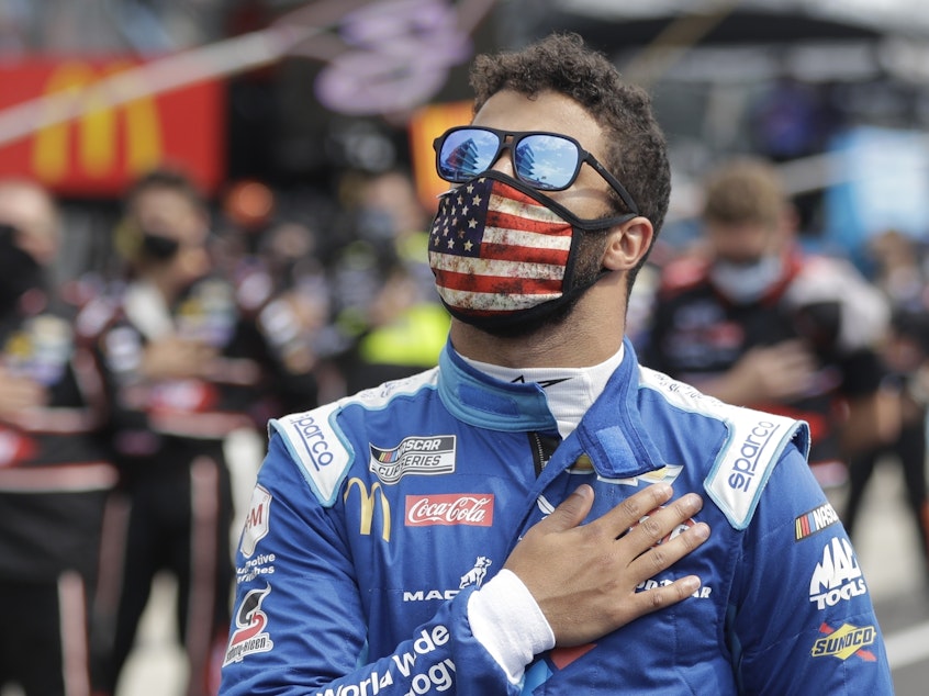 caption: NASCAR Cup Series driver Bubba Wallace stands during the national anthem before a NASCAR auto race at Indianapolis Motor Speedway in Indianapolis, on Sunday.