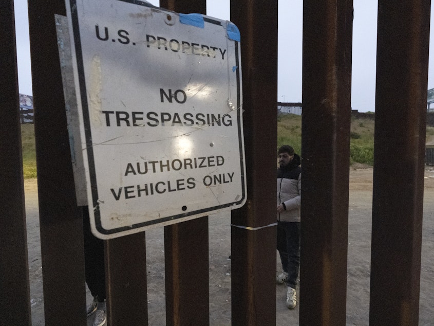 caption: Migrants wait between border walls separating Tijuana, Mexico, and San Diego, to apply for asylum with U.S. authorities on Friday.