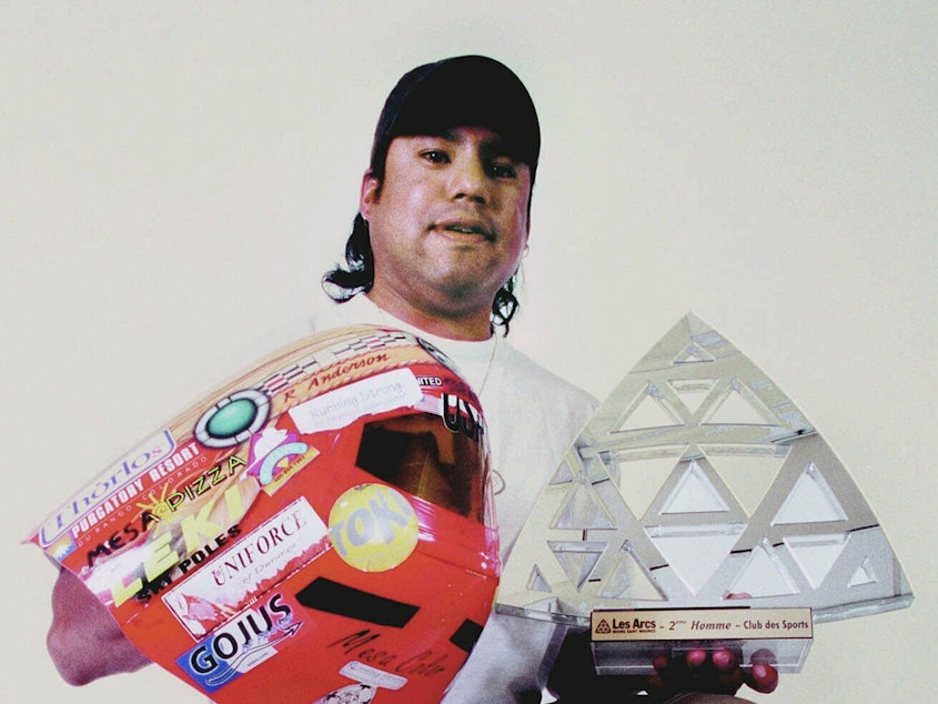 caption: Professional speed skier Ross Anderson holds some of the trophies he won during the 2000-01 winter season. As an indigenous athlete and person of color, Anderson was a trailblazer in professional skiing.