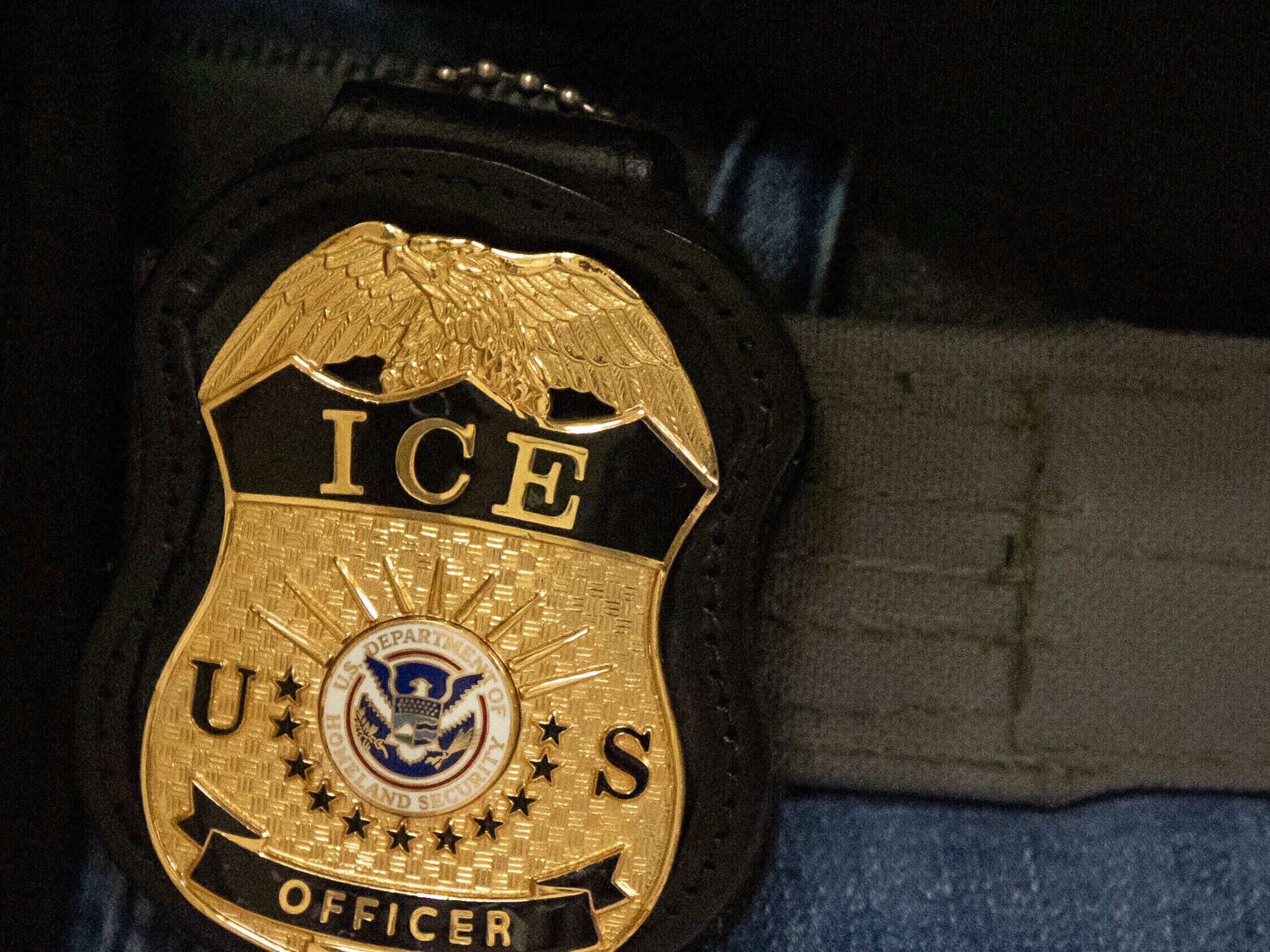 caption: FILE - A federal agent wears an Immigration and Customs Enforcement badge in New York, June 10, 2025.