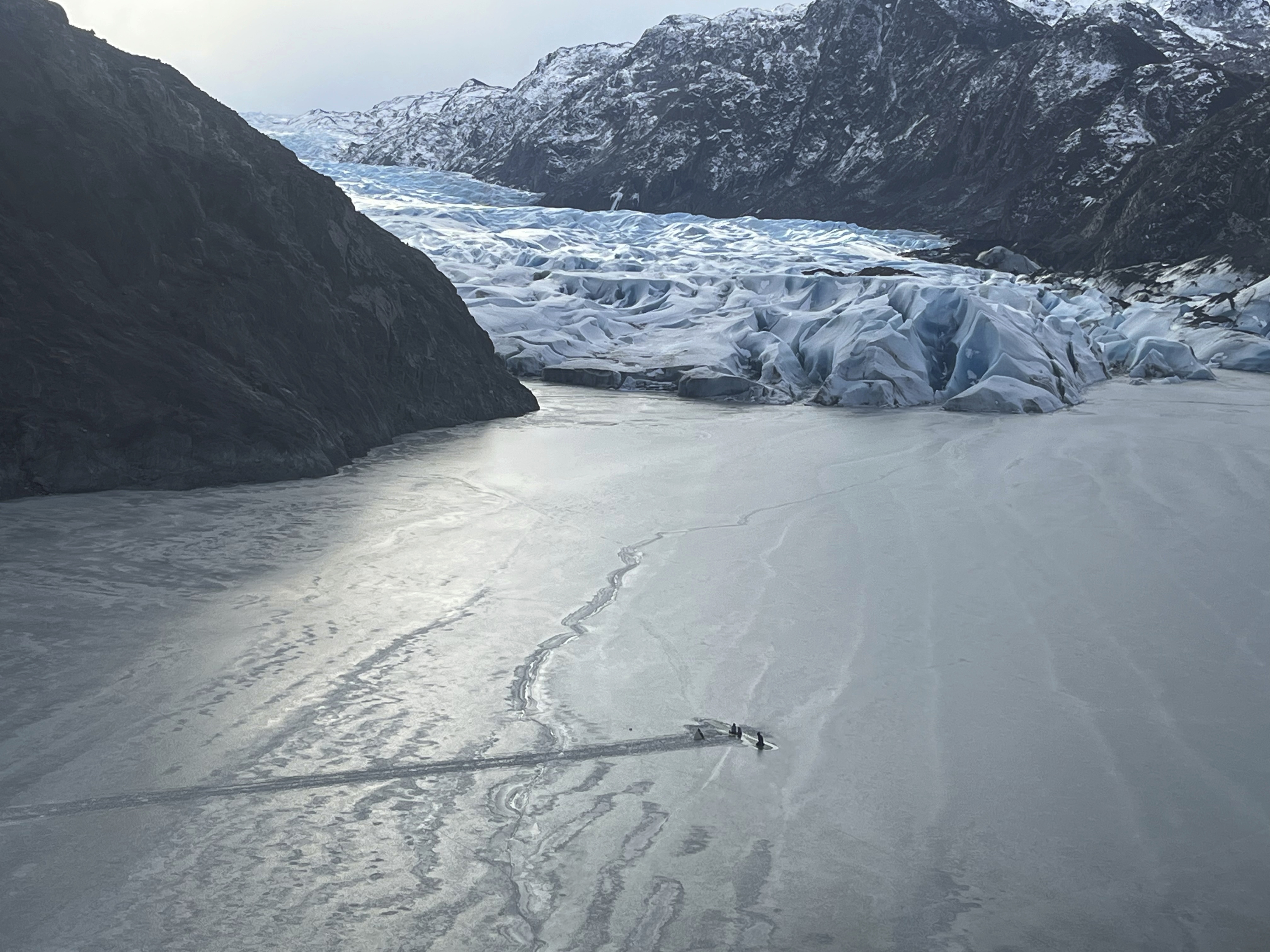 caption: This photo provided by the Alaska National Guard shows an airplane partially submerged into the ice of Tustumena Lake at the toe of a glacier on Monday near Soldotna, Alaska.