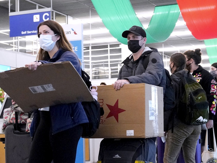 caption: Travelers line up wearing protective masks indoors at O'Hare International Airport in Chicago in December 2021. U.S. District Judge Kathryn Kimball Mizelle voided the national travel mask mandate on Monday.