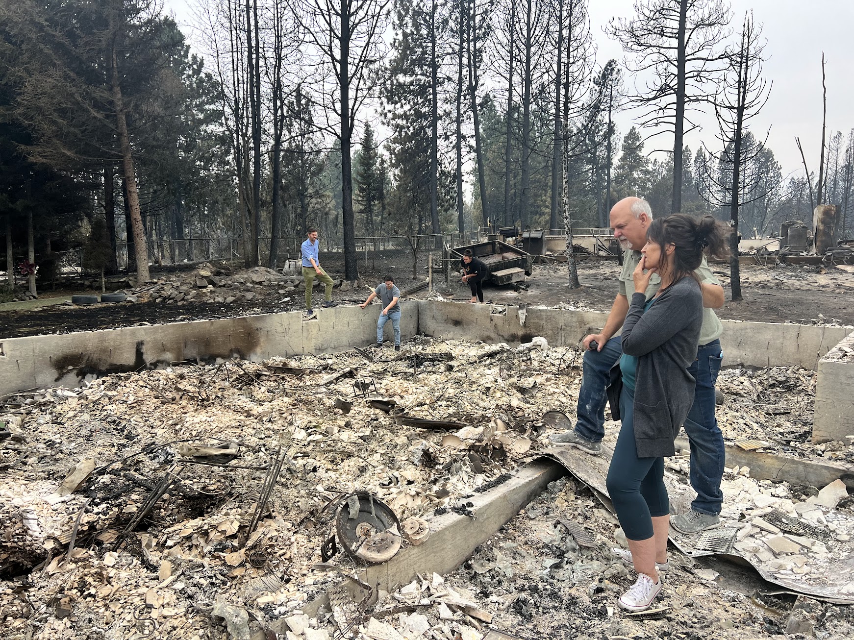 caption:  Mike and Stephanie Zappone comfort each other recently amid the ashes of their home in Medical Lake.