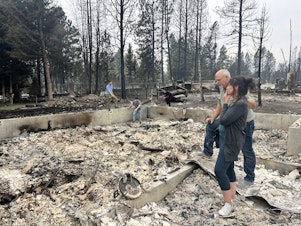 caption:  Mike and Stephanie Zappone comfort each other recently amid the ashes of their home in Medical Lake.