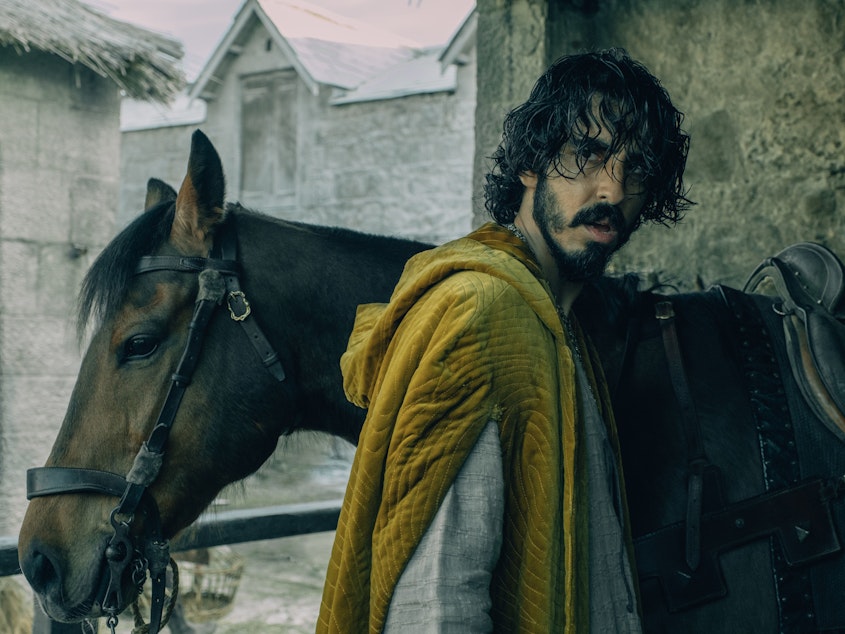 caption: At the beginning of the new movie <em>The Green Knight</em>, Dev Patel's Gawain is the young headstrong nephew of King Arthur. He isn't a knight yet and has a lot to prove.