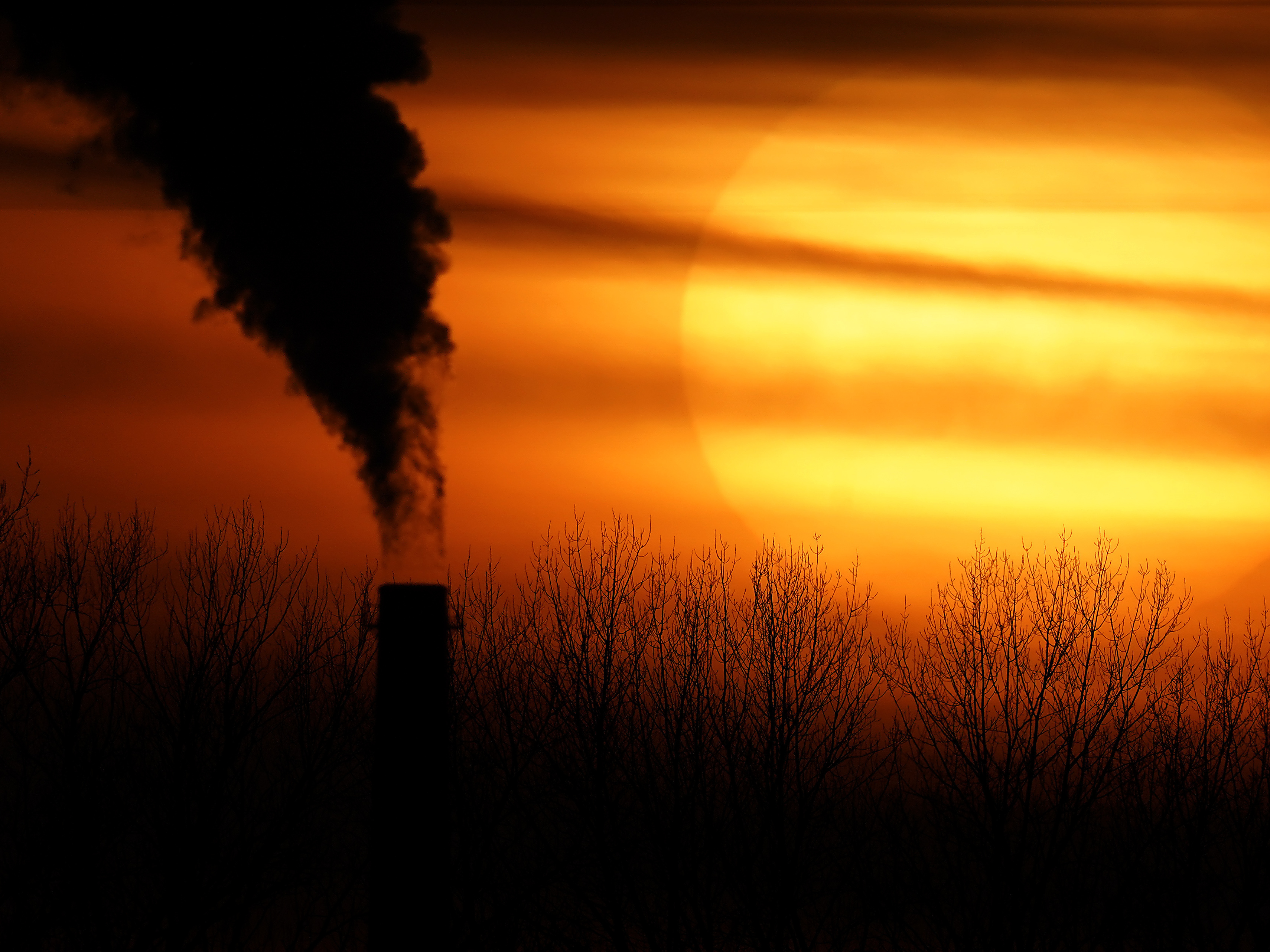 caption: Emissions from a coal-fired power plant are silhouetted against the setting sun in Independence, Mo., in February. President Biden is announcing a new pledge for the U.S. to reduce carbon emissions under the Paris climate agreement.