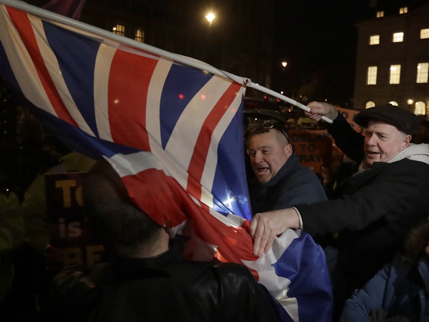 caption: Brexit supporters and opponents shout at each other outside Parliament in London on Thursday, the day that British lawmakers voted to delay Brexit.