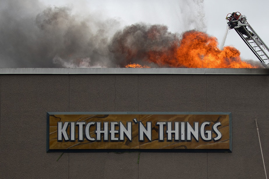 caption: Firefighters work to put out a fire at Kitchen 'N Things on Monday, October 7, 2019, at the intersection of NW Market Street and 24th Avenue Northwest in Seattle.