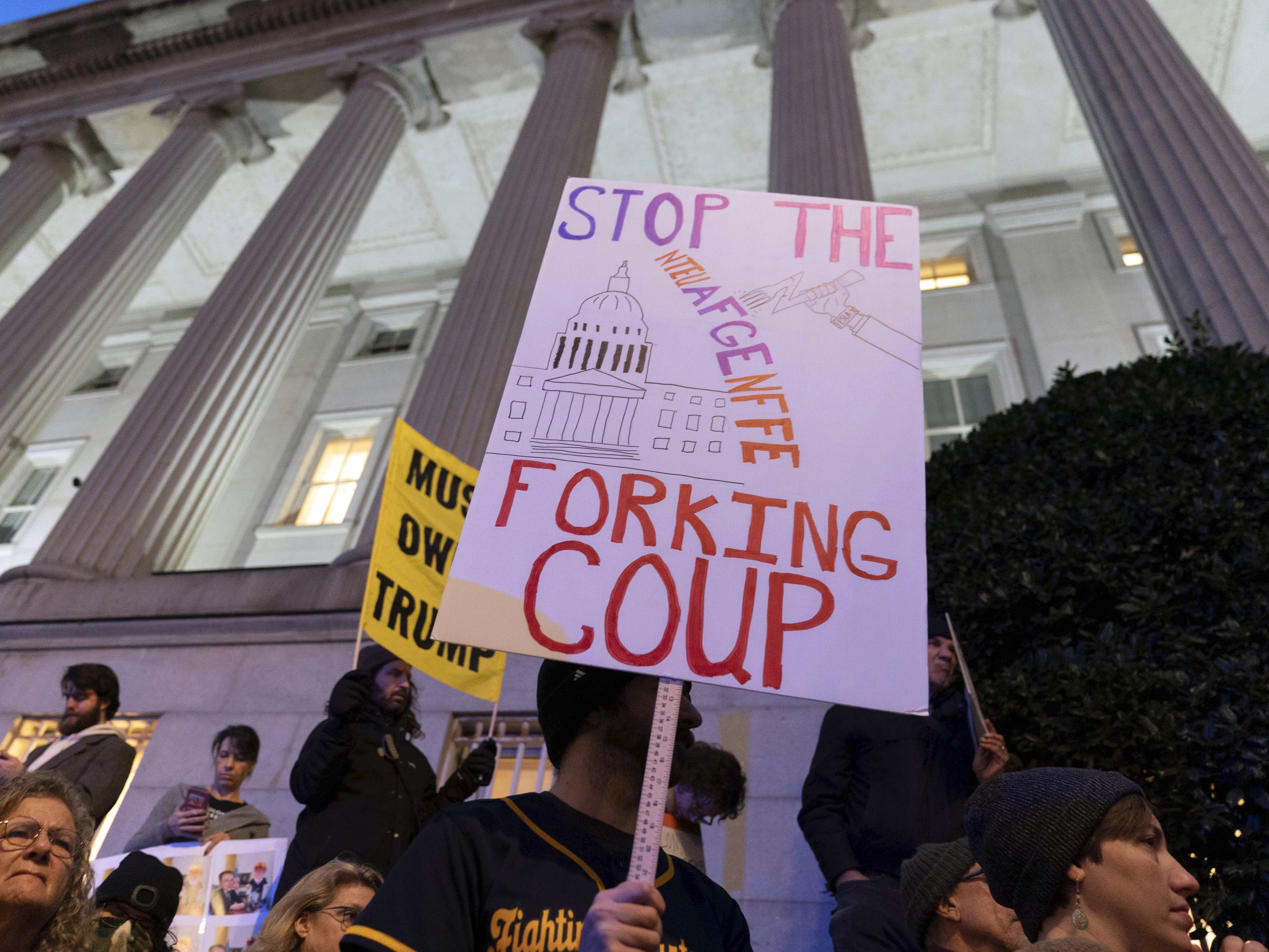 caption: People protest during a rally against Elon Musk, seen as the architect of the "Fork in the Road" offer to federal employees, outside the Treasury Department in Washington, D.C. on Feb. 4, 2025.