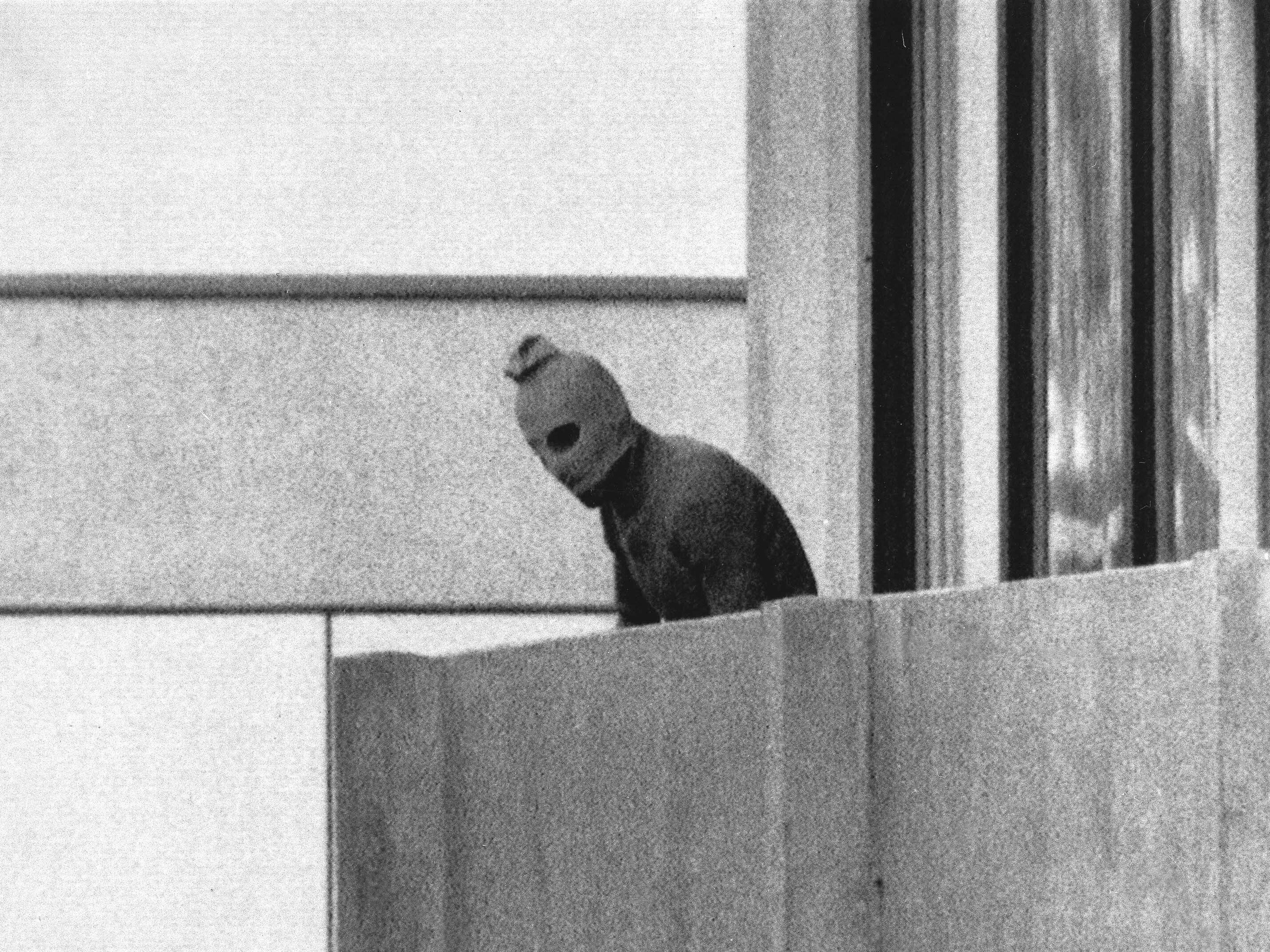 caption: A member of Black September appears on the balcony of the apartment where gunmen held members of the Israeli Olympic team hostage on Sept. 5, 1972. It was the first time a terrorist attack had been broadcast live to a global audience.