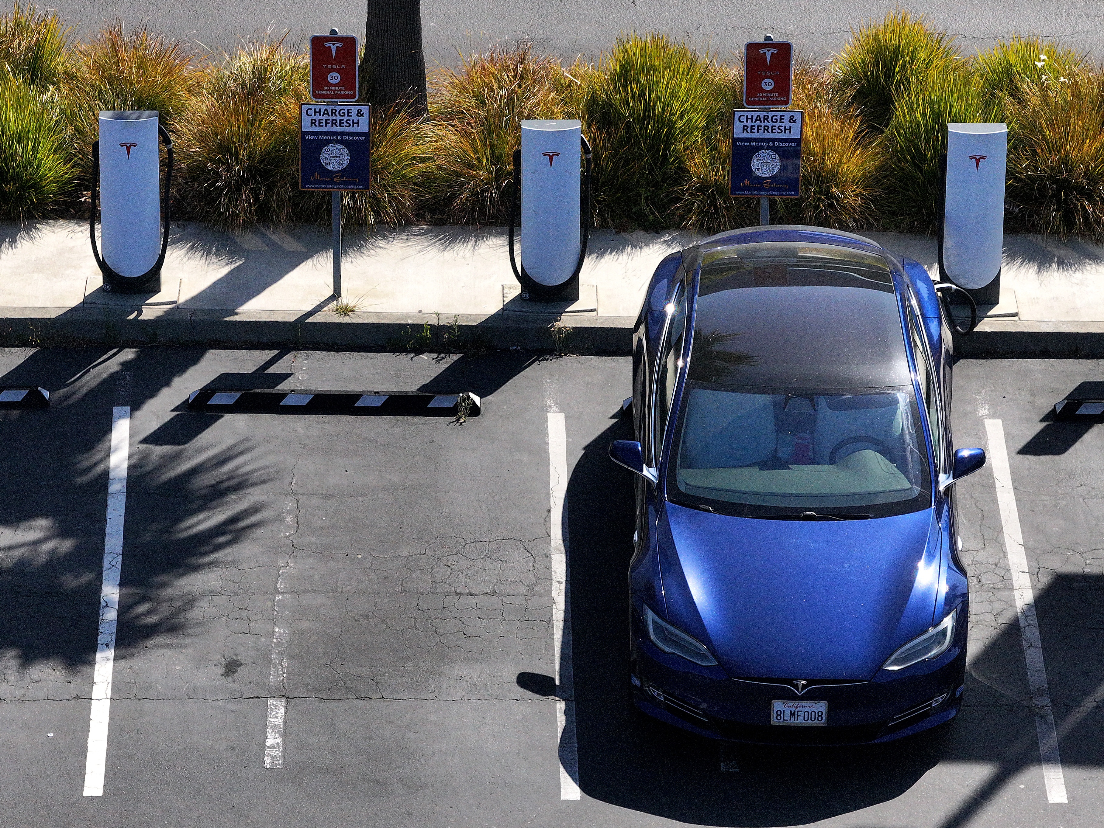 caption: An electric vehicle sits parked at a Tesla charging station in Sausalito, Calif., in June. The tax and spending package under consideration in the Senate could eliminate federal tax credits for buying and purchasing an EV at the end of September — even sooner than a House version of the same bill proposes.