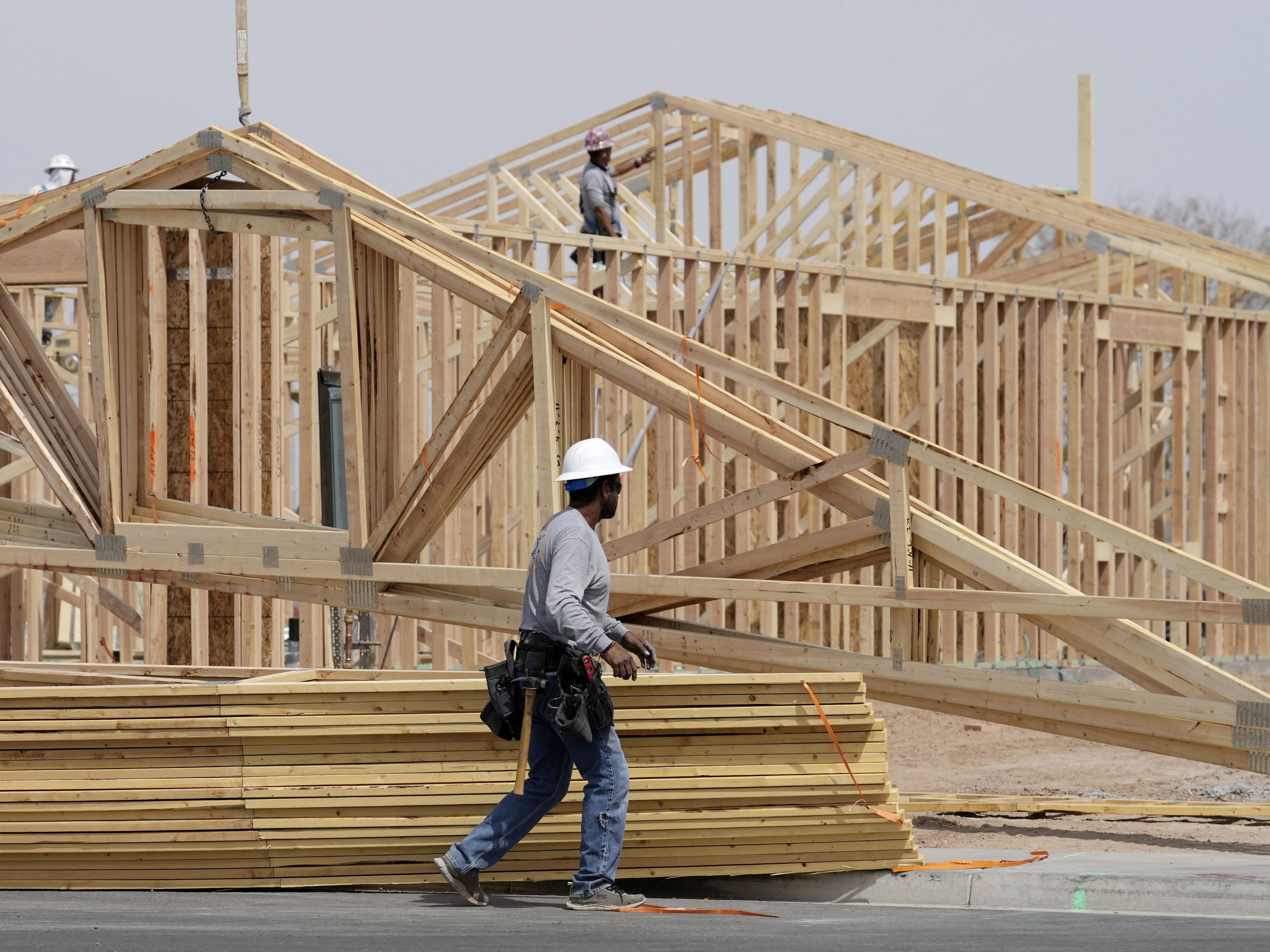 caption: Homebuilding has slowed as Americans face economic uncertainty and high mortgage rates. Here, construction workers install a lumber roof on a new home last month in Laveen, Ariz.