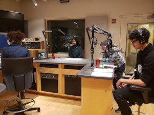 caption: RadioActive youth producers (left to right) Simone St. Pierre Nelson, Marian Mohamed, and Antonio Nevarez record the first youth-produced on-air showcase in December 2019 while RadioActive mentor Kyle Norris looks on.