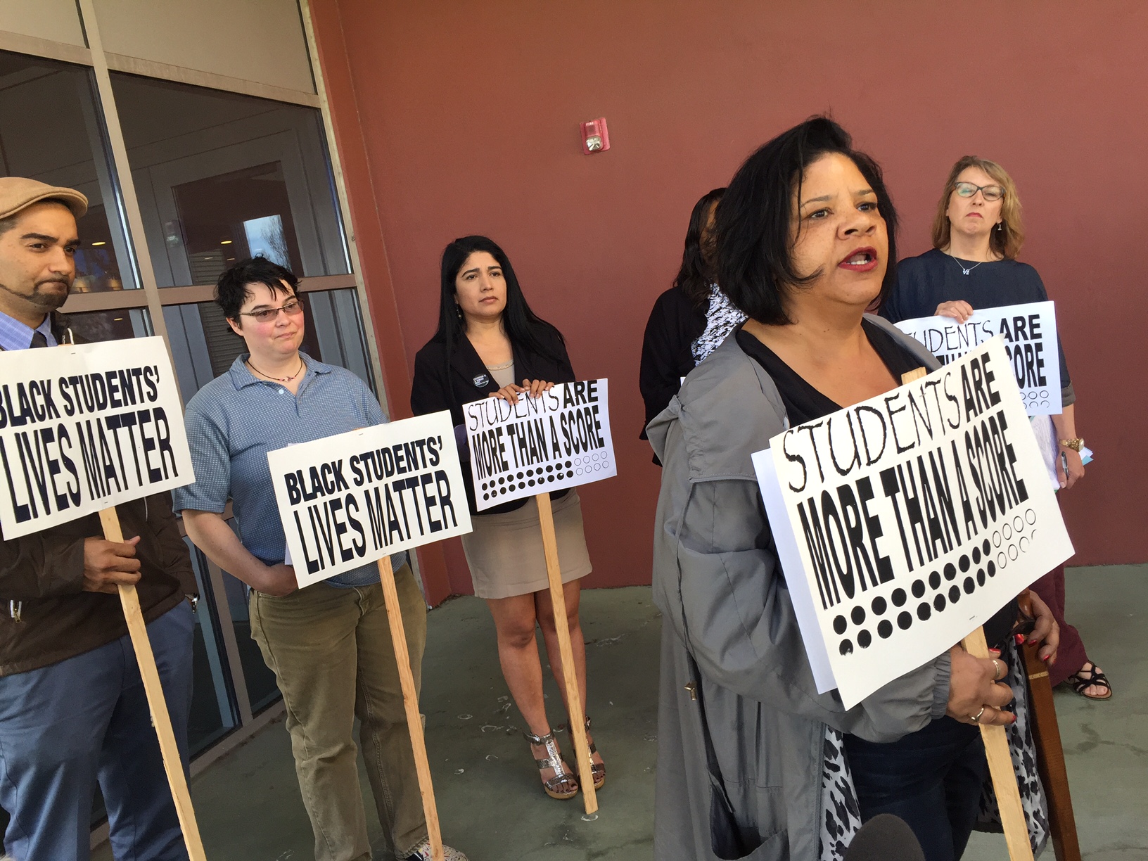caption: Sebrena Burr, right, who has a sixth-grader in Seattle Public Schools, protests the district's standardized tests outside district headquarters.