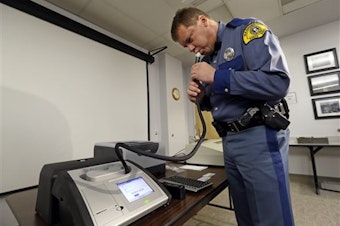 caption: Wash. State Trooper Mel Sterkel demonstrates the patrol's newest breath testing instrument, used to measure alcohol levels in drivers suspected of drunken driving, Nov. 5, 2014, in Seattle.
