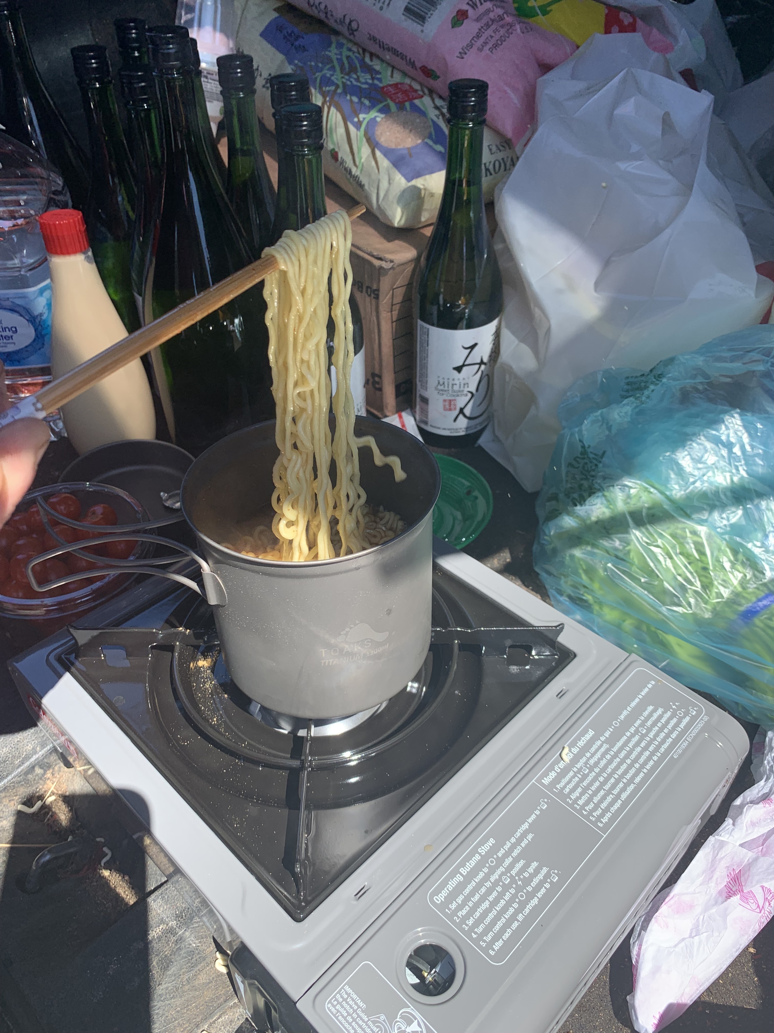 caption: Chef Josh Ratza checks the instant ramen he's cooking on a portable camp stove inside the back of his Subaru.