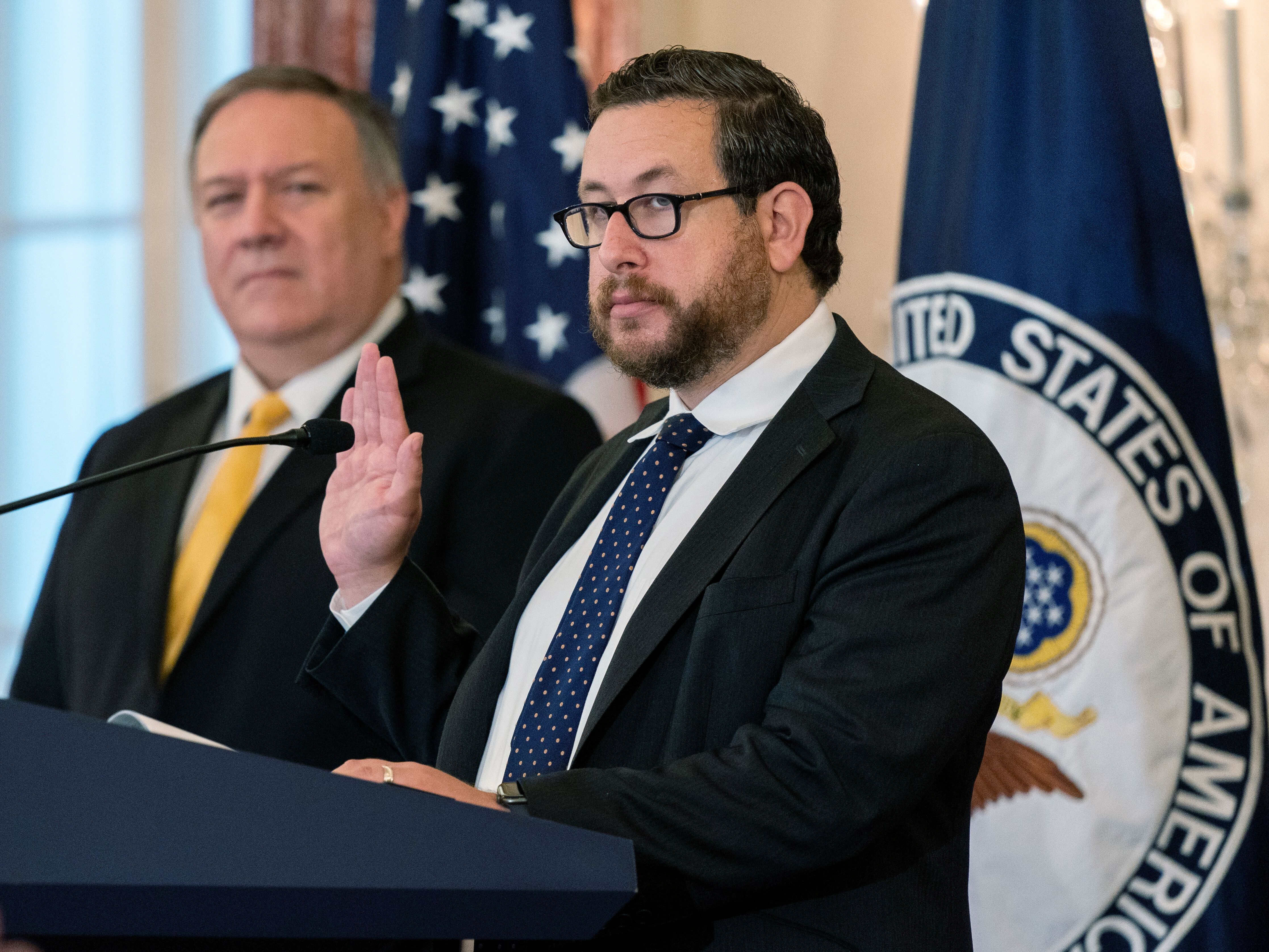 caption: Joseph Edlow (R), now the U.S. Citizenship and Immigration Services director, administers the Oath of Allegiance to twelve candidates for U.S. citizenship during a naturalization ceremony hosted by the USCIS at the State Department in October 2020.
