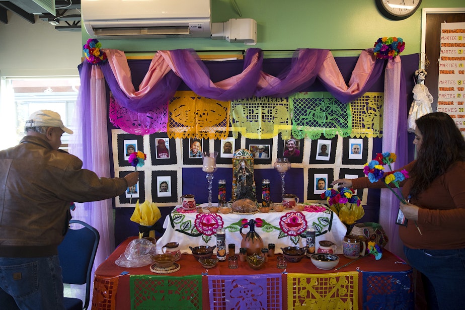 caption: Miguel Hernandez, left, and Lucina Carrillo add flowers to their Day of the Dead altar on Tuesday, October 29, 2019, at Casa Latina in Seattle.