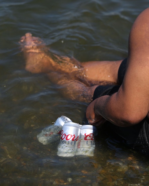 caption: Dee Black cools his beer in Lake Washington, Monday, June 28, as temperatures rose to 108 in Seattle.
