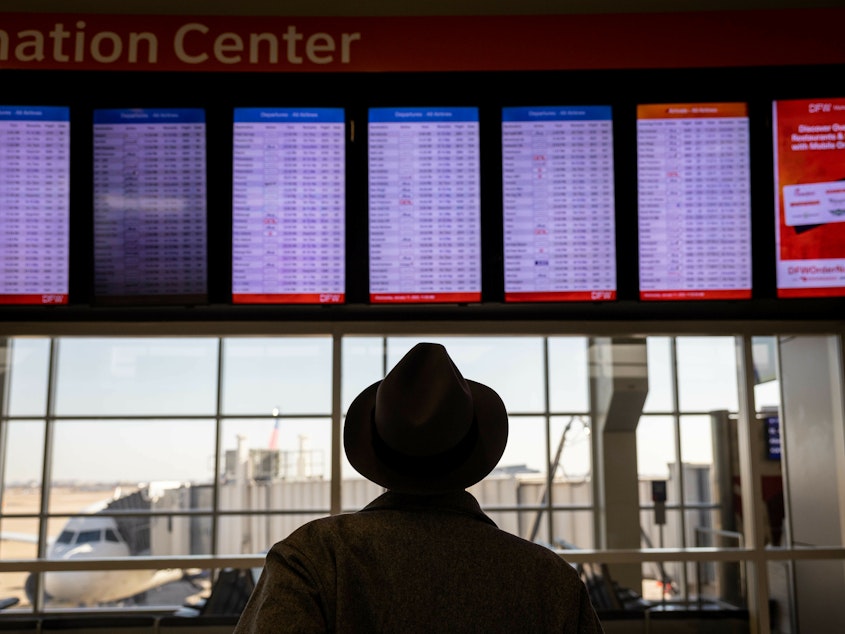 caption: A passenger at Dallas-Fort Worth International Airport looks at a flight board after a system outage grounded thousands of flights throughout the country on Jan. 11.