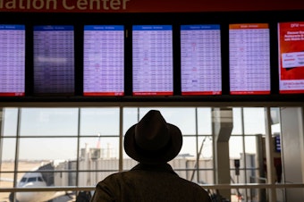 caption: A passenger at Dallas-Fort Worth International Airport looks at a flight board after a system outage grounded thousands of flights throughout the country on Jan. 11.
