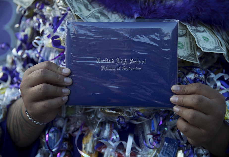 caption: Garfield High School senior Jabez Taualo holds his diploma after an in-person graduation ceremony on Tuesday, June 15, 2021, at Memorial Stadium in Seattle. "It's a true honor to be here today," said Taualo.