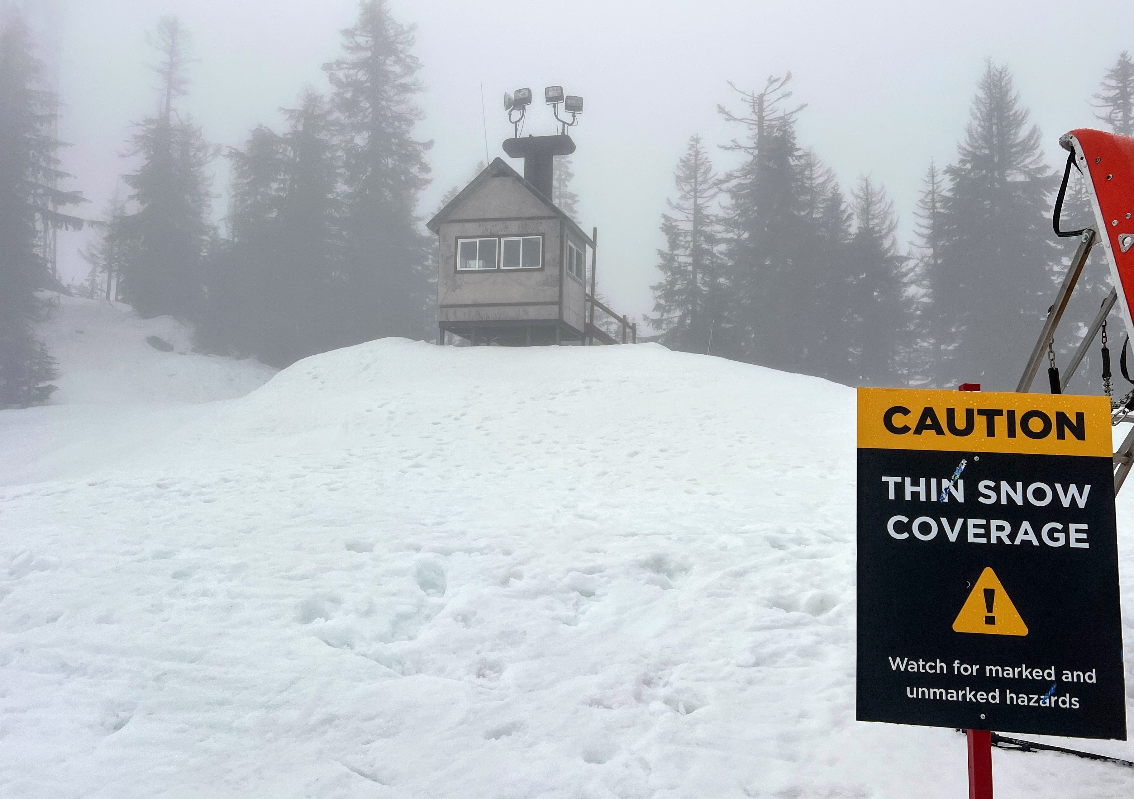 caption: Signs warn skiers and snowboarders to watch for rocks and tree tops on Jan. 31, 2026, at the top of Pacific Crest chairlift at The Summit at Snoqualmie ski resort in Washington state.