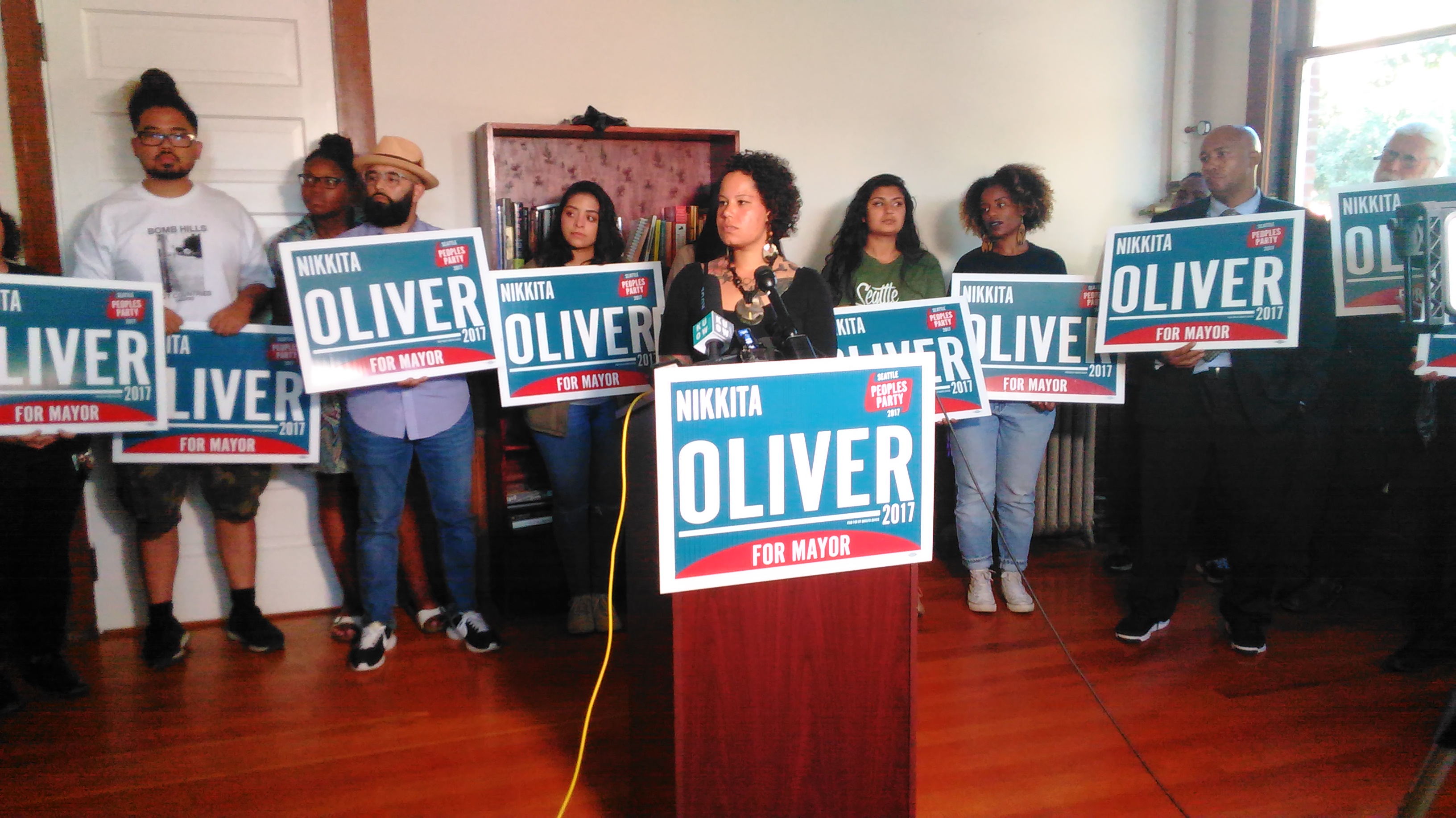caption: Nikkita Oliver, surrounded by supporters, declares 3rd place in Seattle's mayoral race a victory.