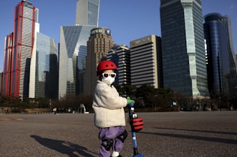 caption: A South Korean child masks up to ride a scooter on Feb. 27, 2020 in Seoul.