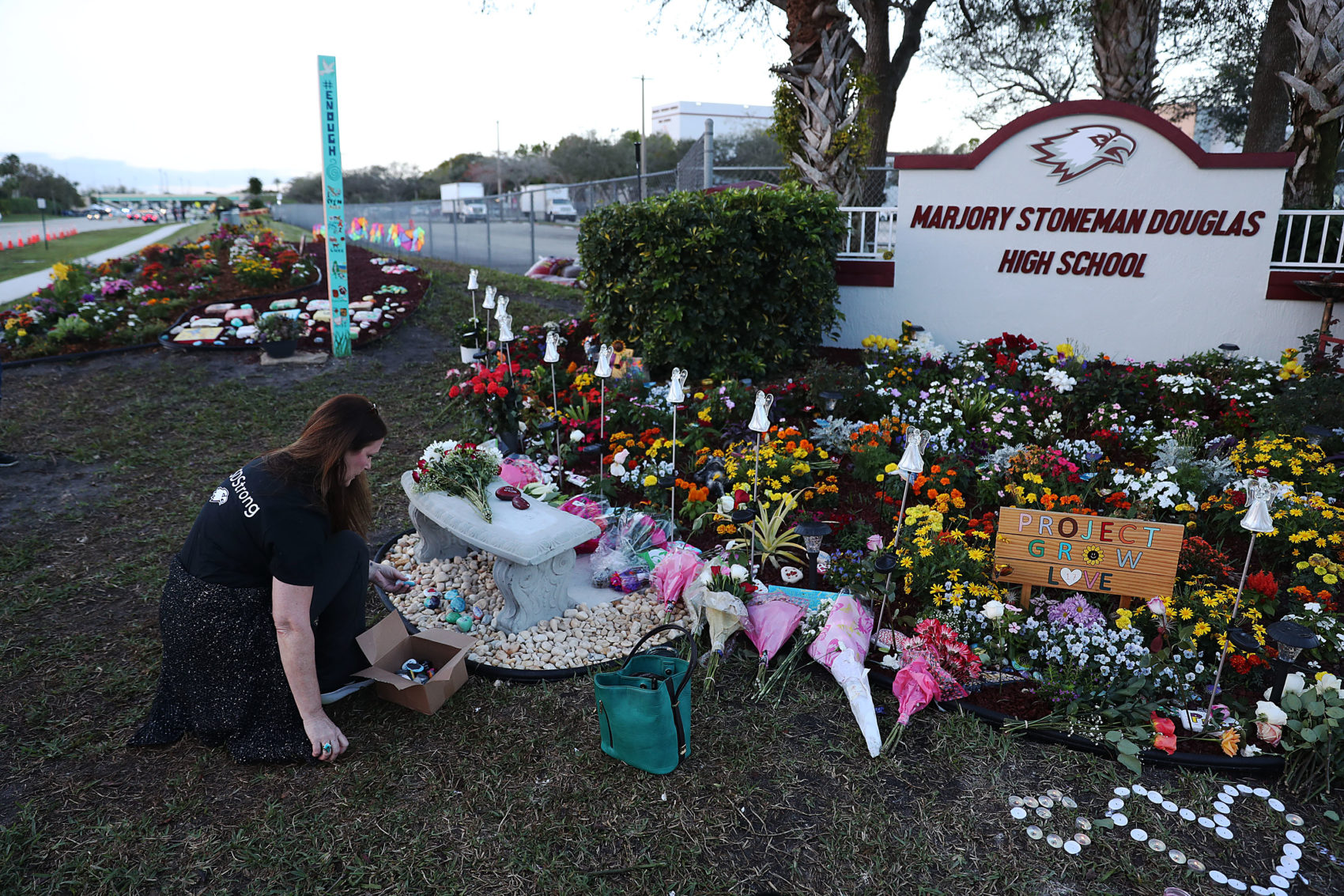 caption: PARKLAND, FLORIDA - FEBRUARY 14:  Suzanne Devine Clark visits a memorial setup at Marjory Stoneman Douglas High School for those killed during a mass shooting on February 14, 2019 in Parkland,  Florida. A year ago on Feb. 14th at Marjory Stoneman Douglas High School 14 students and three staff members  were killed during the mass shooting. (Photo by Joe Raedle/Getty Images)
