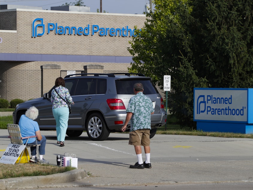 caption: Abortion protesters attempt to hand out literature as they stand in the driveway of a Planned Parenthood clinic in Indianapolis on Aug. 16.
