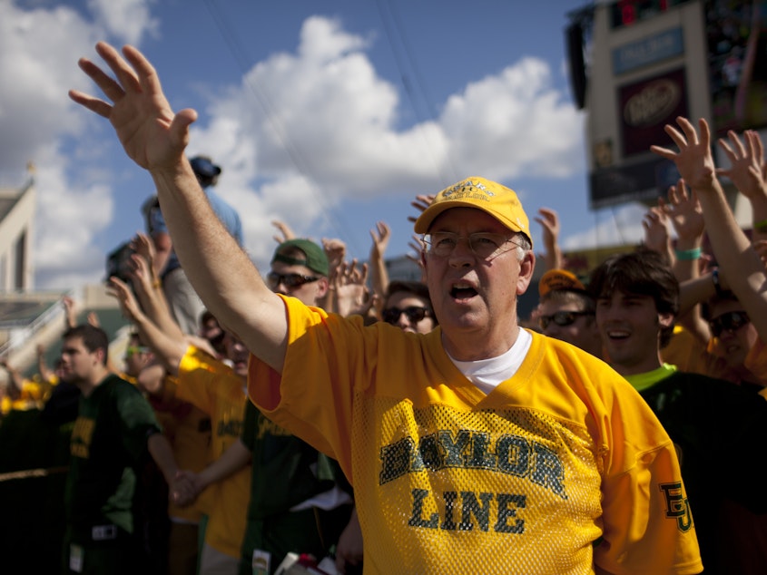 caption: Ken Starr cheers with Baylor University students before a 2012 game against the University of Kansas Jayhawks in Waco, Texas.
