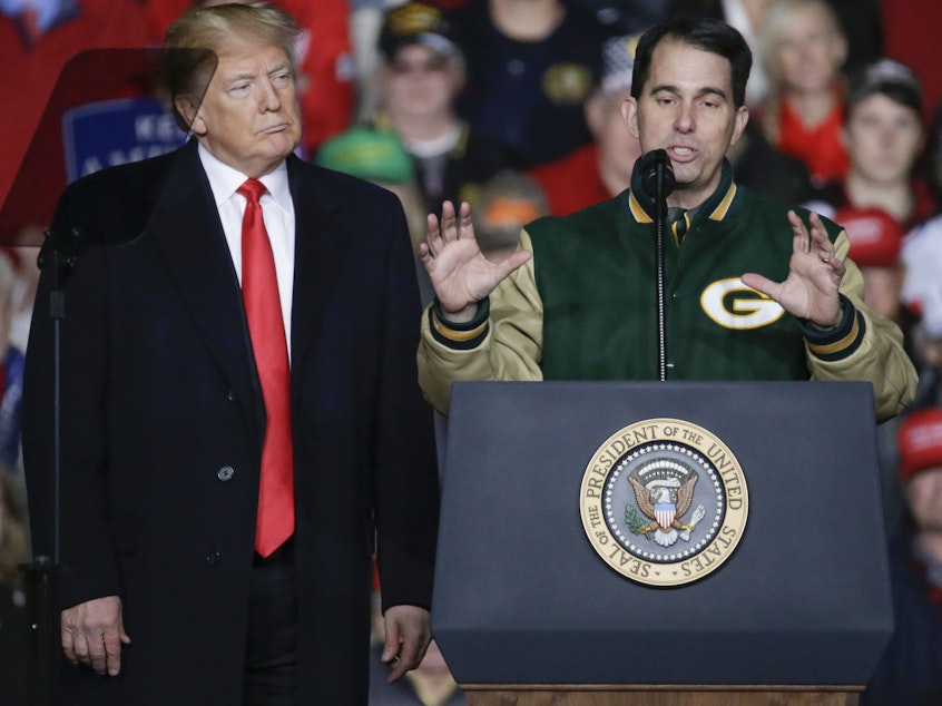 caption: With President Trump at his side, Wisconsin Gov. Scott Walker speaks during a rally in Mosinee, Wis., on Oct. 24.