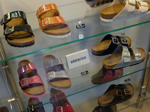caption: Birkenstock sandals are on display in the window of a store in Berlin.