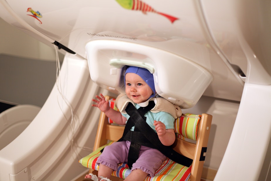 caption: A baby sits in a magnetoencephalography brain scanner at the UW Institute for Learning and Brain Science while listening to vowel sounds.