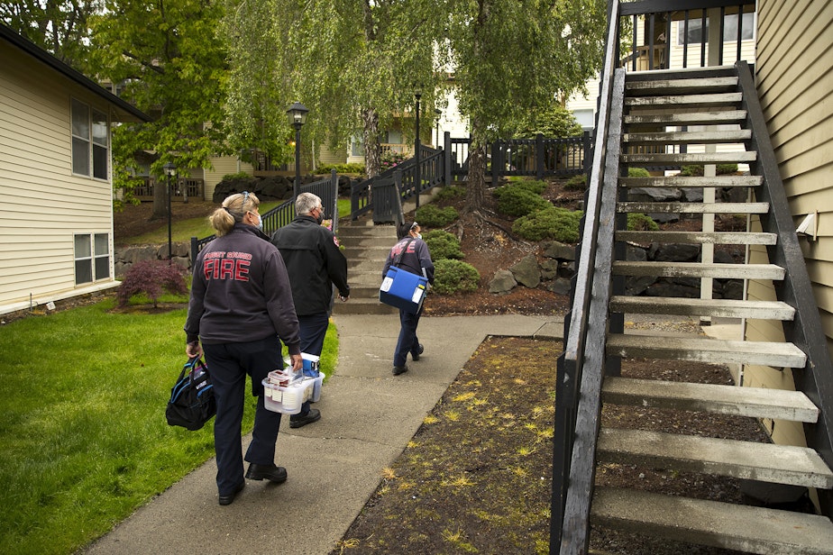 caption: From left, Puget Sound Regional Firefighter Nikki Smith, Public Information Officer Joe Root and firefighter Jessi Nemens walk to the home of a homebound individual to administer a Moderna Covid-19 vaccine, on Monday, May 24, 2021, in Kent. 
